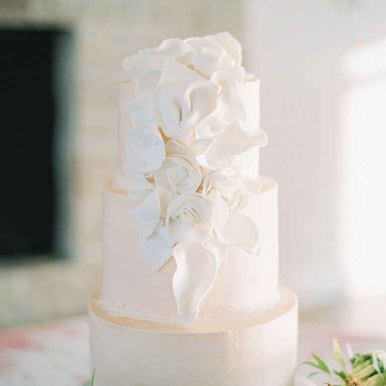 White three-tier wedding cake with white flower decorations