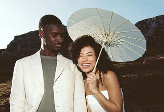Woman holding a sun umbrella holding onto her partner's arm