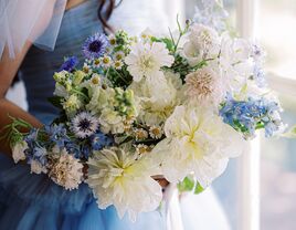 Bride wearing blue dress as something blue holding bouquet with blue flowers