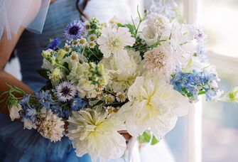 Bride wearing blue dress as something blue holding bouquet with blue flowers