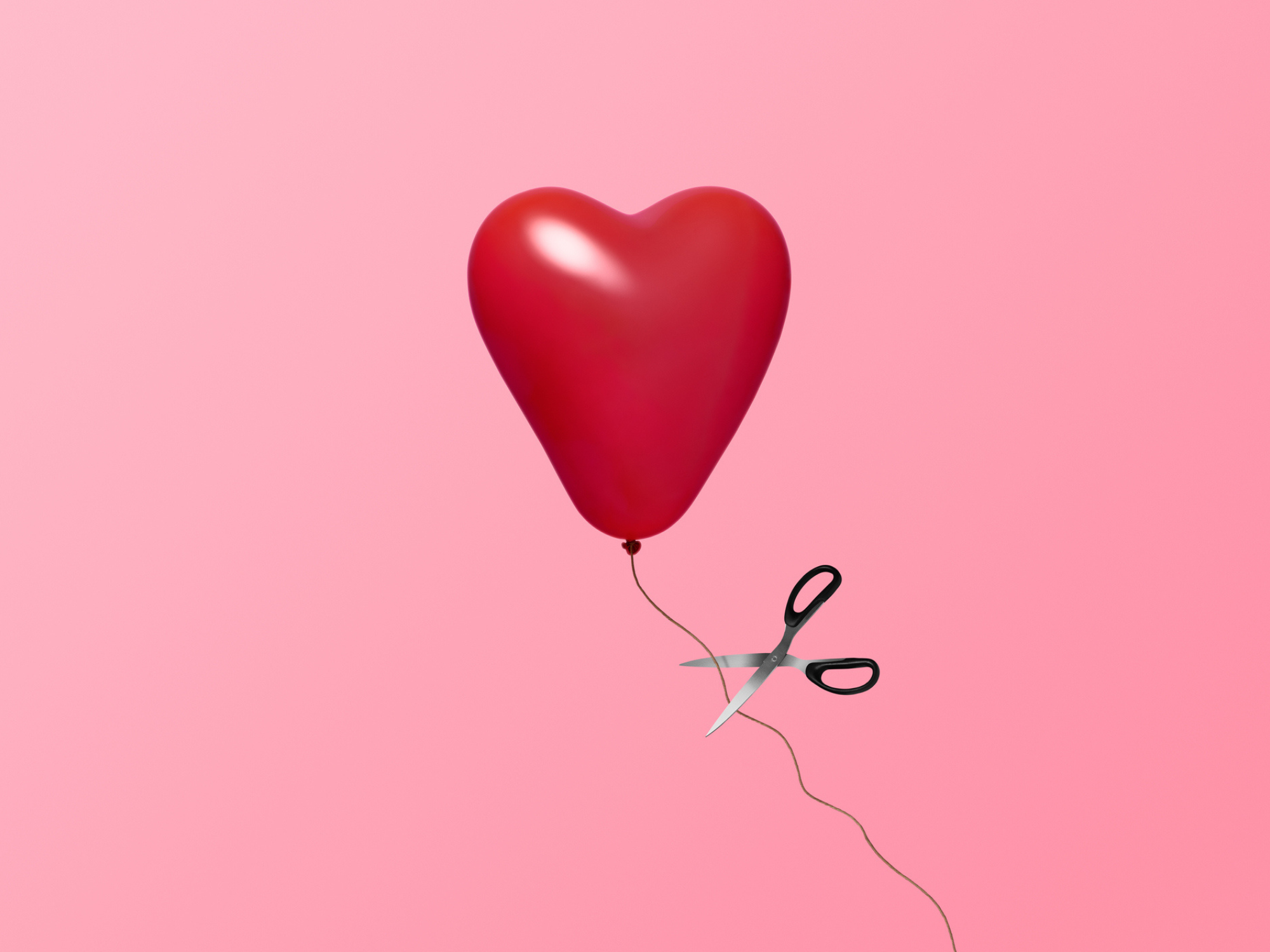 Heart balloon being cut with scissors