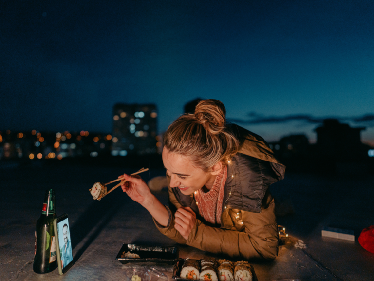 Woman on phone with partner eating sushi on long distance date