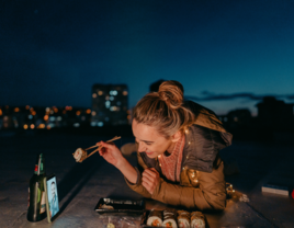 Woman on phone with partner eating sushi on long distance date