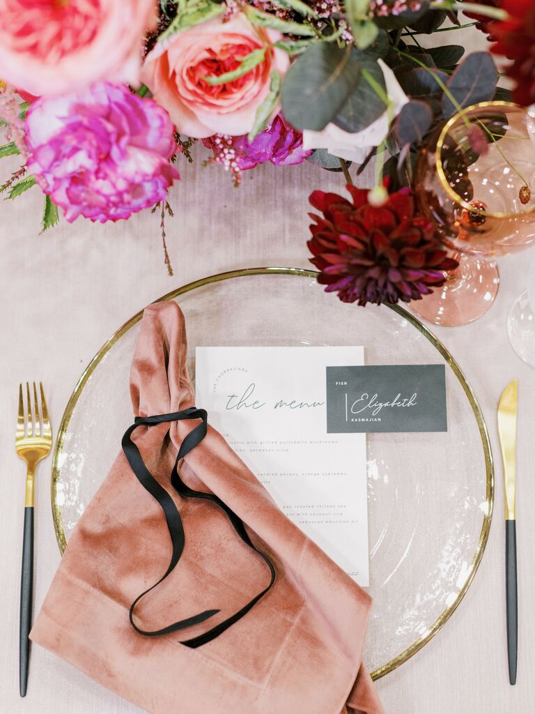 modern wedding place setting with blush napkin and gold rim glass plates with black flatware