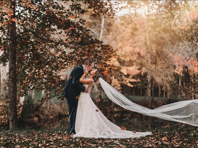 Couple kissing in the forest surrounded by falling autumn leaves