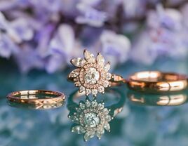 rose gold engagement ring with floral halo and wedding bands