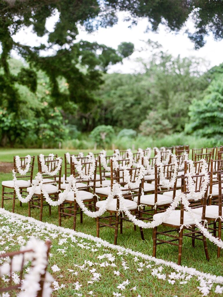 Aisle featuring white floral garlands and flower petals. 