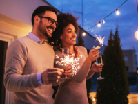 Couple holding champagne flutes and sparklers at rooftop engagement party