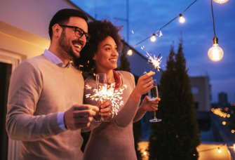 Couple holding champagne flutes and sparklers at rooftop engagement party