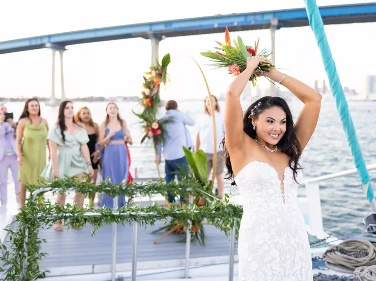Bride tossing bouquet at wedding reception on Triton Charters