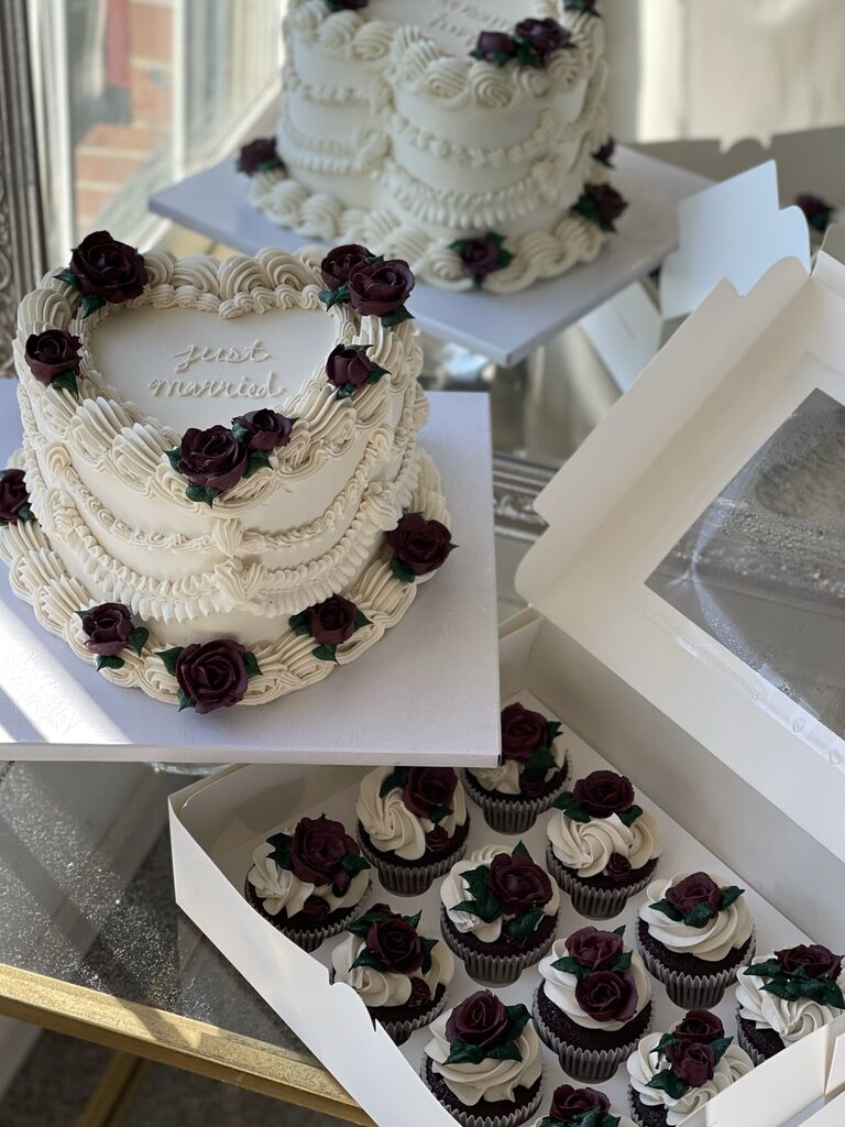 elegant heart shaped wedding cake with dark burgundy roses and matching cupcakes