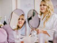 Bride glances in mirror while getting ready for her ceremony. 
