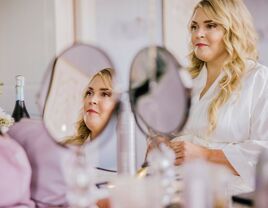 Bride glances in mirror while getting ready for her ceremony. 