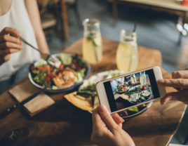 man taking photo of girlfriend at dinner