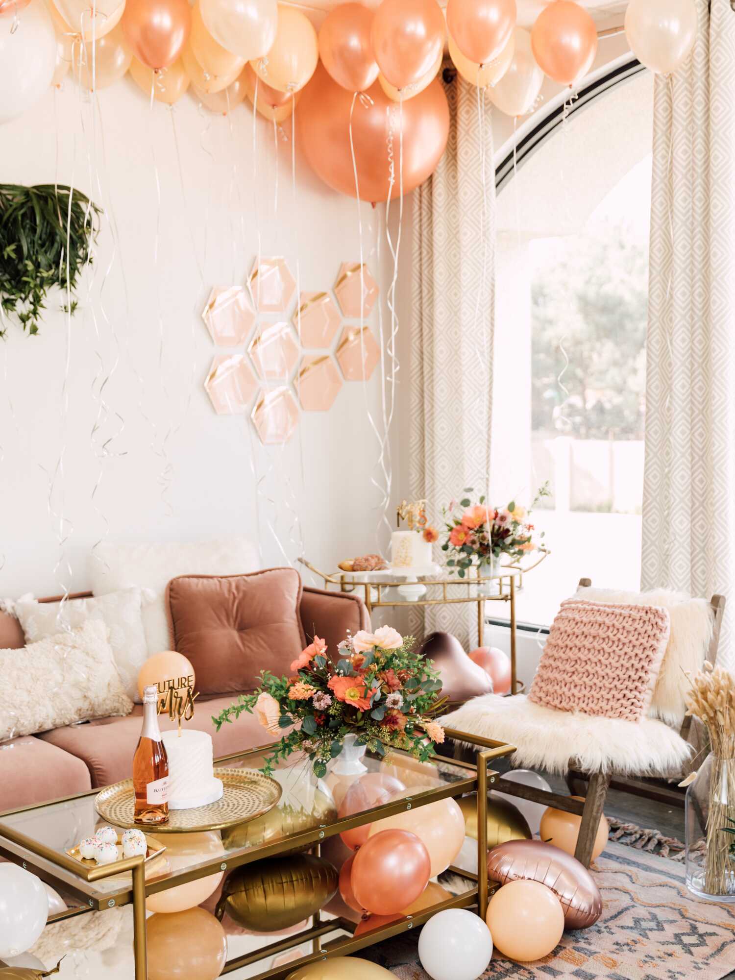 Peach and gold balloons covering the ceiling of a party