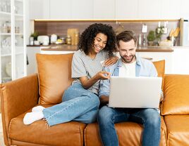 Couple sitting on couch looking at laptop
