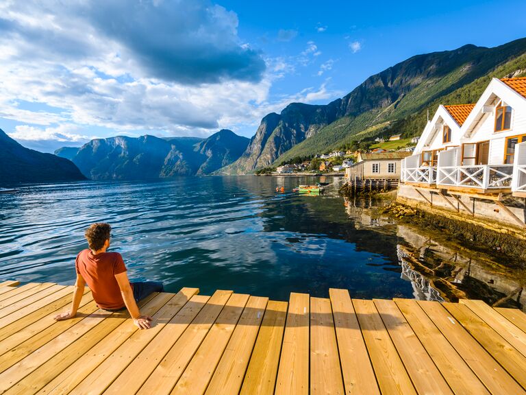 Man sitting on wooden pier admiring a Norwegian Fjord, Western Norway