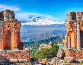 Ruins of ancient theater in Taormina, Sicily and Etna volcano in the background 