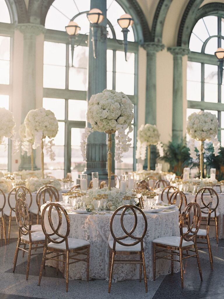 Elegant baroque wedding centerpieces with tall white florals and antique gold vases