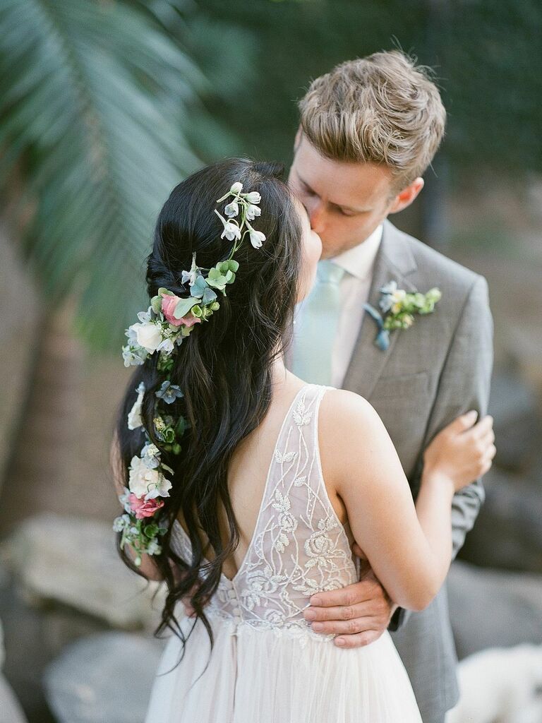 Bride wears fresh flowers and vines in her long hair. 