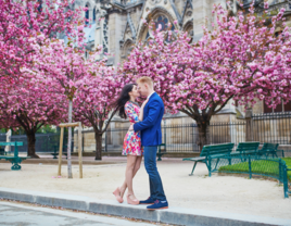 Couple kissing in front of cherry blossom trees