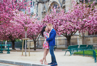 Couple kissing in front of cherry blossom trees