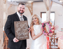 Groom holding sign and bride holding tourbine bouquet. 