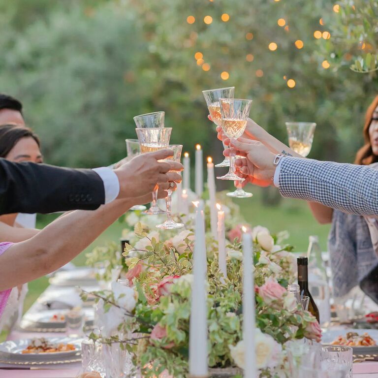 guests enjoying occasion dinner outside and raising glasses