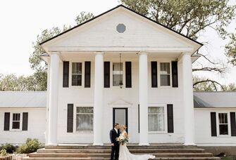 Happy newlyweds in front of the grand mansion at Prairie Meadow Events