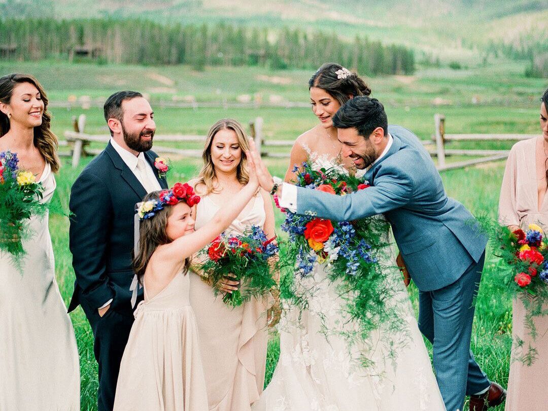 Flower girl high-fiving groom near bride during wedding ceremony