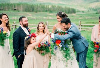 Flower girl high-fiving groom near bride during wedding ceremony