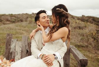 Bride with twisted half-up hairstyle sitting in groom's lap