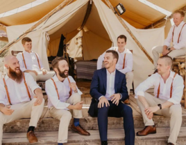 Groom and groomsmen in boho wedding outfits sitting together and laughing