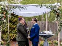 Grooms exchanging vows under chuppah at Jewish wedding ceremony