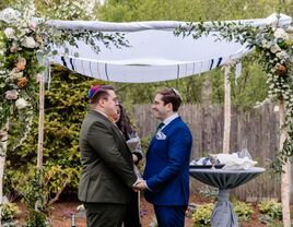 Grooms exchanging vows under chuppah at Jewish wedding ceremony