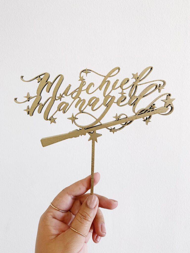 Wooden 'Mischief Managed' cake topper in gold script with stars and wand detail