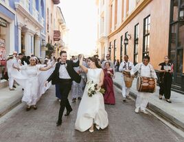 Newlyweds celebrate on a colorful city street with music and dancing. 