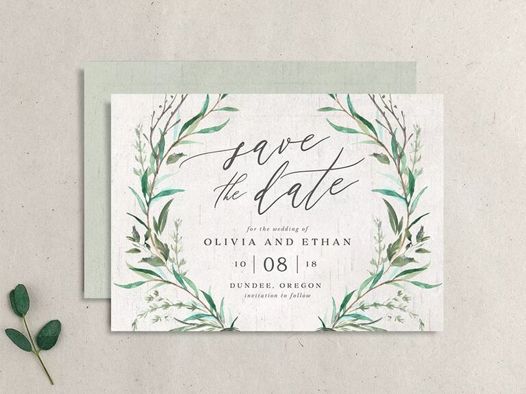Greenery framing event details and 'save the date' in calligraphy on off-white background