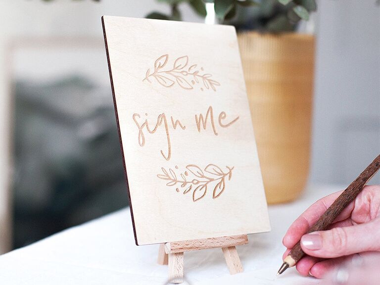 'Sign me' engraved in wooden sign with vine designs