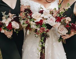 close up of bride and bridesmaids holding winter wedding bouquet with light pink garden roses, dark red roses and ivy vines