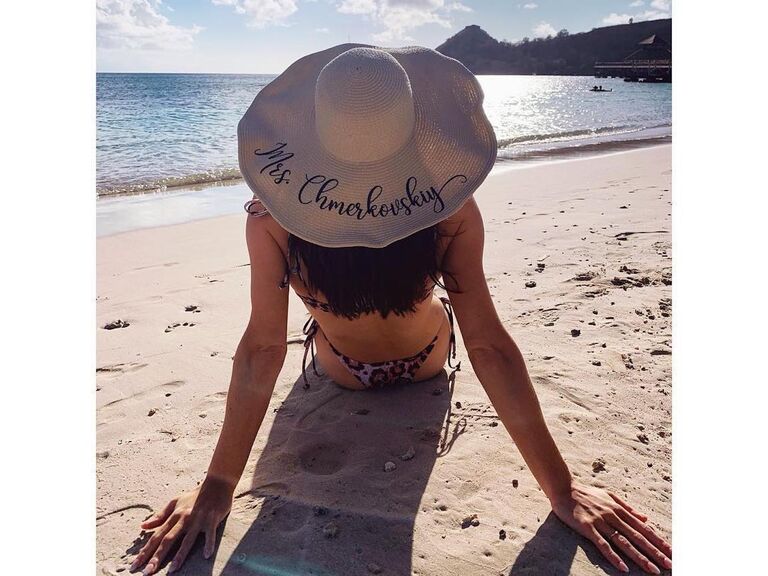 Sitting on beach wearing hat, which reads: "Mrs. Chmerkovskiy."