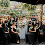 Brides surrounded by their wedding party and guests dressed in black