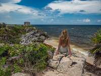 woman sitting on cliff in tulum mexico