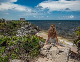 woman sitting on cliff in tulum mexico