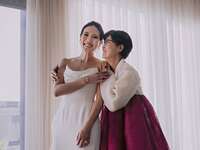 bride in wedding dress smiles with mother of the bride wearing a korean hanbok