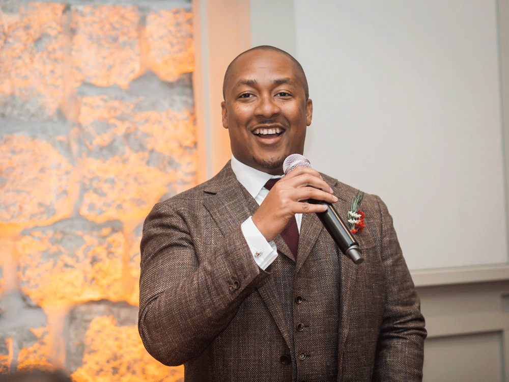Best man smiling and holding microphone.