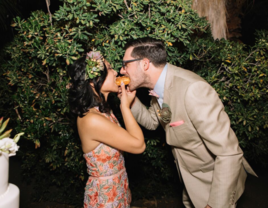 Bride and groom sharing late night wedding snack donut