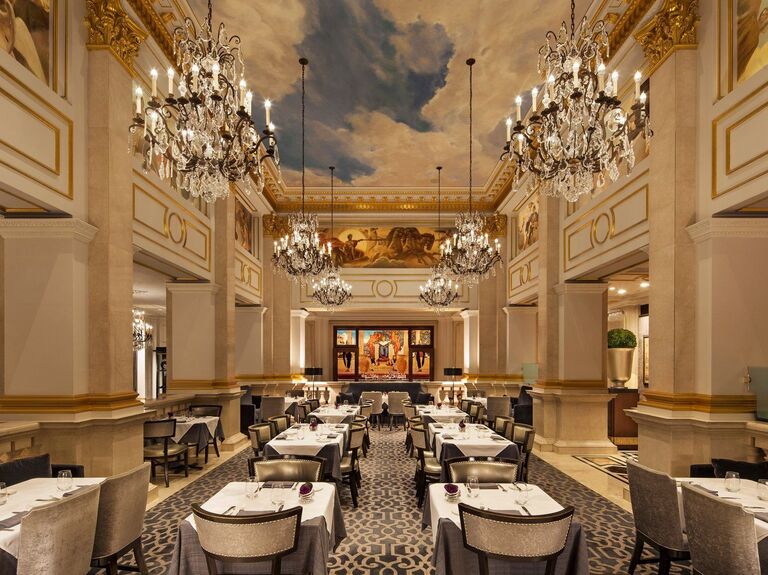 Inside view of grand event space with gold and marble molding, ornate chandeliers, and murals