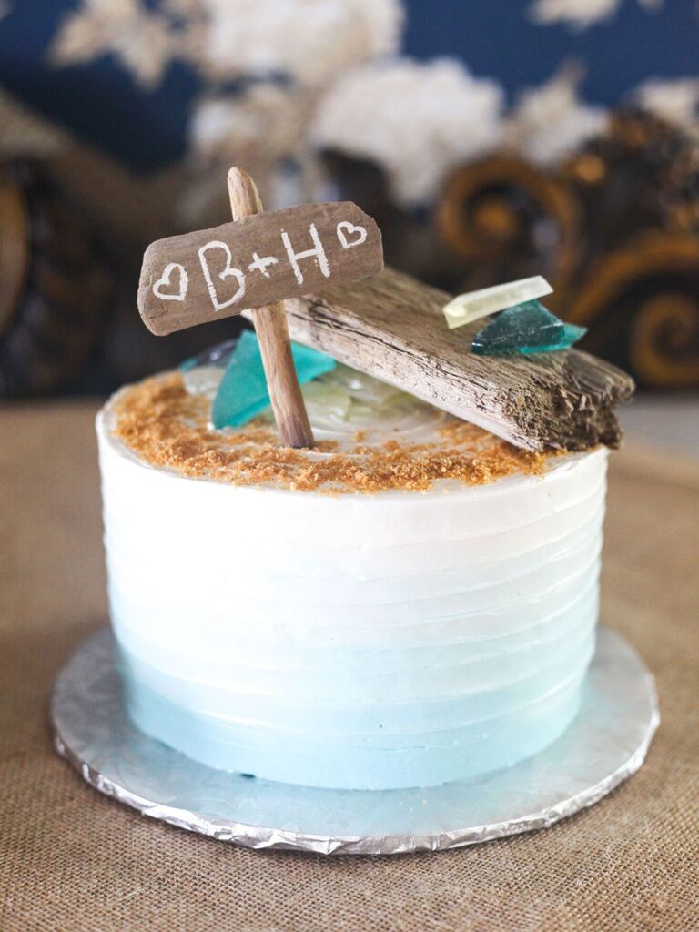 Small one-tier beach wedding cake with sandy top and custom cake topper