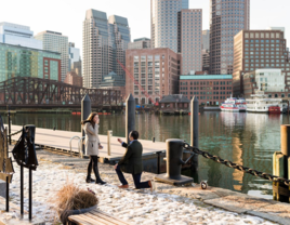 Man proposing to woman in front of Boston skyline